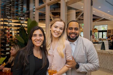 people posing for a photo smiling at a happy hour